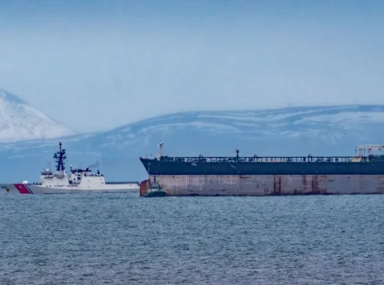 Oil tanker Marinera escorted by a U.S. Coast Guard vessel with snowy mountains in the background.