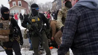 A man confronts federal agents while a person is detained, amid protests in Minneapolis against the presence of ICE agents.
